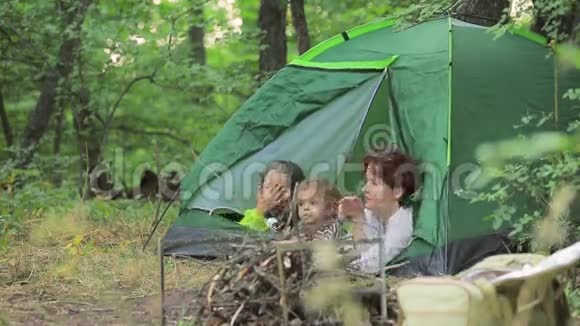 女孩和小男孩欣赏躺在帐篷里的大自然视频的预览图
