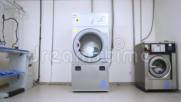 女工人从洗衣房的烘干机里拿衣服视频的预览图