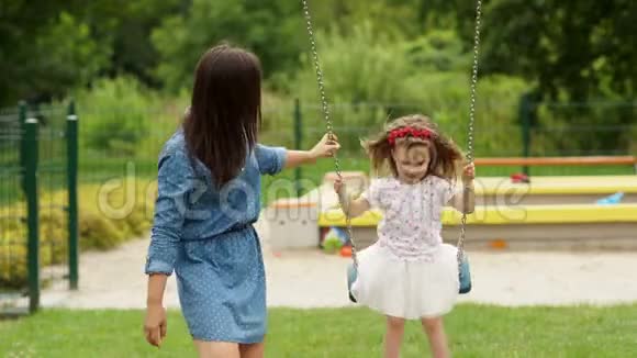 在游乐场的夏日温暖的日子里家庭在一起度过快乐的时光小女孩骑着秋千出门视频的预览图