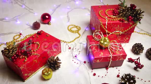 红色手工礼品盒和圣诞装饰品金色苹果和带有闪亮灯笼的凸起物俯视视频的预览图