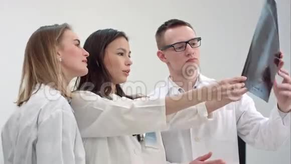 三位年轻医生在看脊柱x线视频的预览图