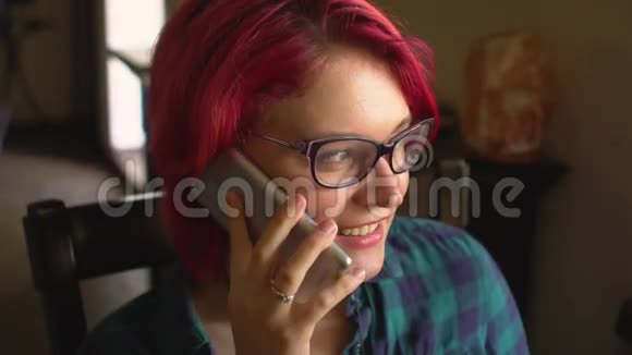 美丽的年轻女子在智能手机上说话想在咖啡馆里开窗视频的预览图