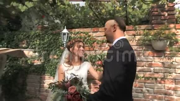 一对漂亮的新婚夫妇在砖墙的背景下视频的预览图