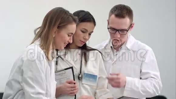 三位微笑的医生在使用平板电脑时讨论X光视频的预览图