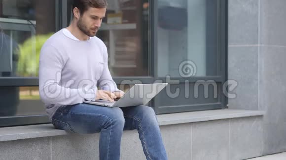 帅哥在办公室外坐着做笔记本电脑视频的预览图