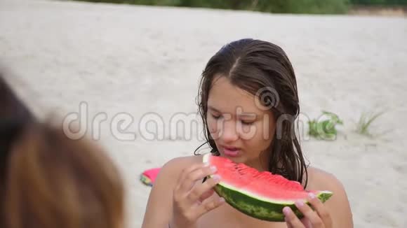 孩子们在海滩上吃西瓜少女粉刺吃西瓜慢动作视频概念视频的预览图
