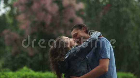 在雨中欢笑情感的夫妻拥抱和亲吻两个情人很高兴在户外一起度过视频的预览图