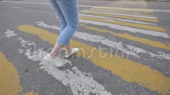 一个穿蓝色牛仔裤的年轻女孩穿过人行横道视频的预览图