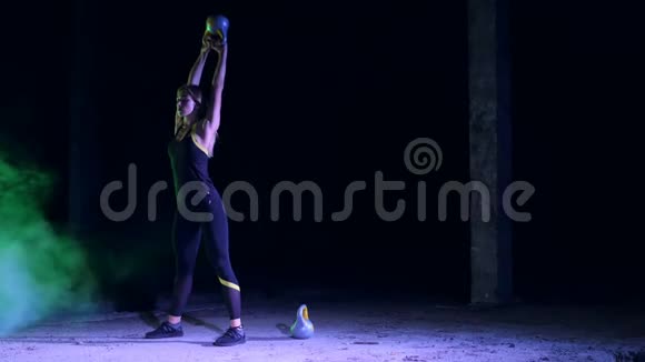 运动美丽年轻的女人做各种力量锻炼与重量晚上在多种颜色的灯光下视频的预览图