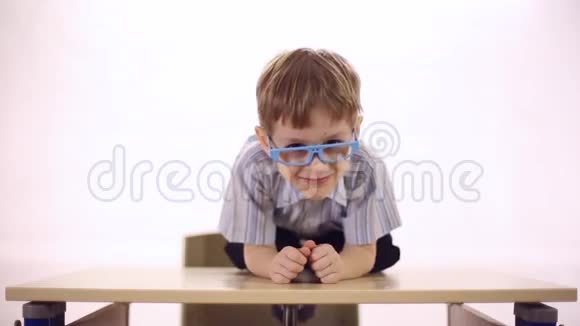 带着眼镜坐在学校课桌上的滑稽男孩视频的预览图