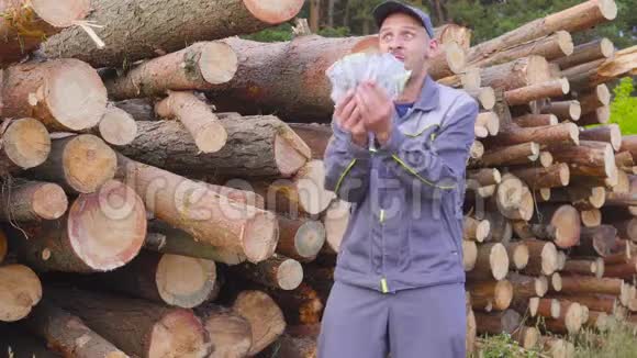 快乐的工人伐木工或木匠有一大笔钱靠近一堆原木锯木成功商业概念视频的预览图