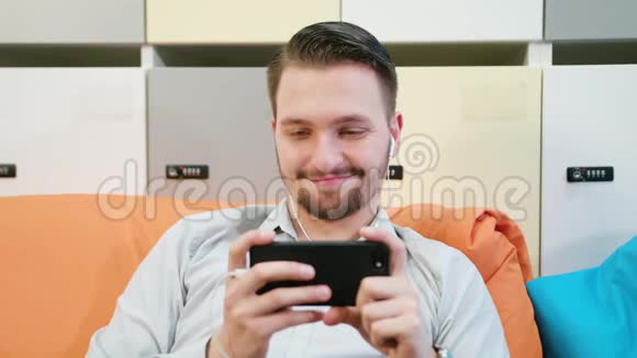男人在室内看智能手机上的视频视频的预览图