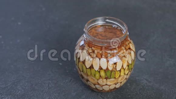 打开罐子在黑色桌子上放蜂蜜中的坚果视频的预览图
