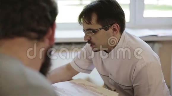 医生带着眼镜和一件白色的实验室外套建议病人视频的预览图