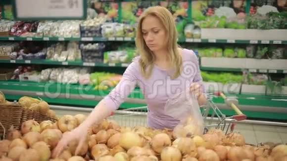 一个女人在超市的蔬菜货架上买蔬菜土豆视频的预览图
