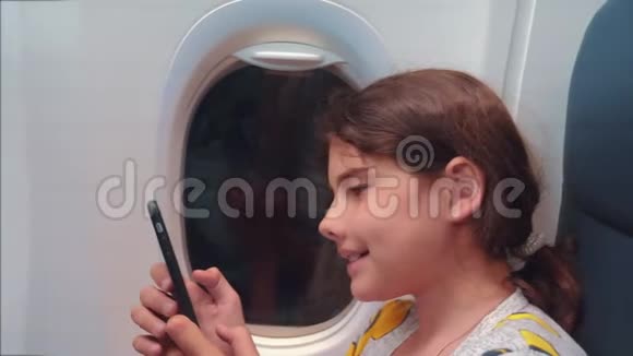 航空飞机概念小女孩正坐飞机在窗户旁边聊天看着里面视频的预览图