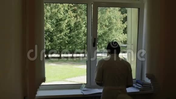 医生穿着白色长袍站在窗口检查文件视频的预览图