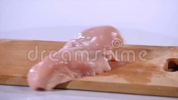 2块生鸡片落在木板上动作缓慢视频的预览图