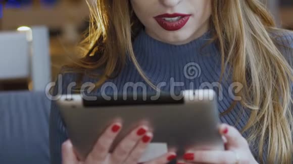 快乐的年轻女人用平板电脑工作在咖啡馆里微笑慢慢地视频的预览图