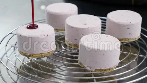 一个糖果师在制作小的单份蛋糕时他用红熔糊或果冻覆盖蛋糕视频的预览图