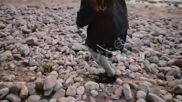 在岸上行走的女孩的后景小女孩在石头上迈着不确定的步子视频的预览图