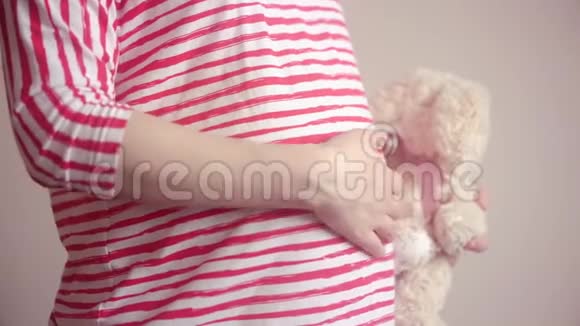 孕妇手拿毛绒玩具用手摸肚子视频的预览图