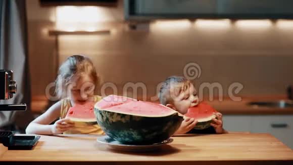 兄妹坐在厨房的桌子旁男孩和女孩吃西瓜享受水果视频的预览图