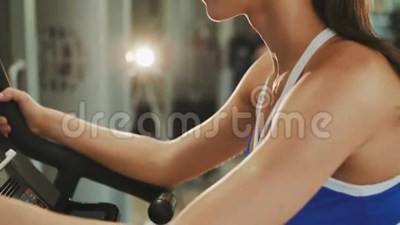 漂亮的女运动员在健身房里骑运动自行车锻炼4K视频的预览图