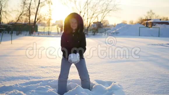 一个女孩把雪扔到头上落在夕阳背景下的雪上视频的预览图