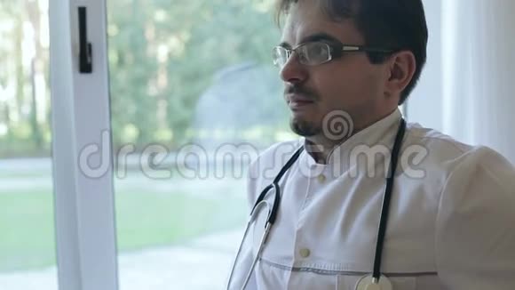 医生穿着一件白色外套脖子上戴着听诊器站在窗口说话视频的预览图