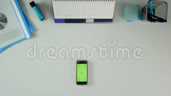 一个男人坐在他的办公桌前用他的手机然后是钱桌子上有办公用品视频的预览图