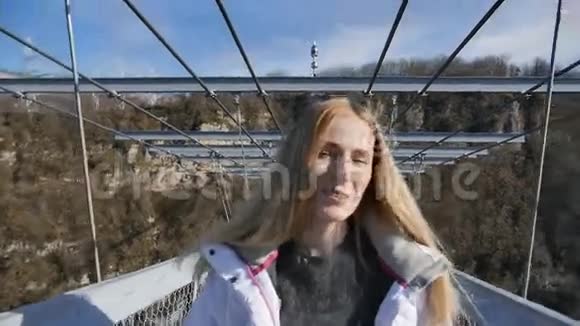 女人在镜头前穿过峡谷的高桥向前走视频的预览图
