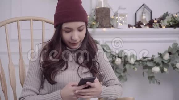 年轻的亚洲女人坐在家里客厅里用灰色毯子包裹的椅子上视频的预览图