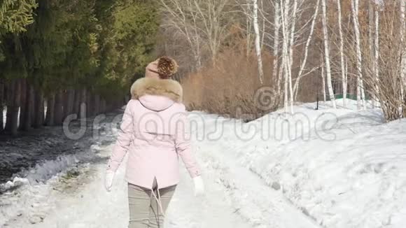 幸福美丽的女人在阳光明媚的日子里走在冬天的森林里慢动作视频的预览图