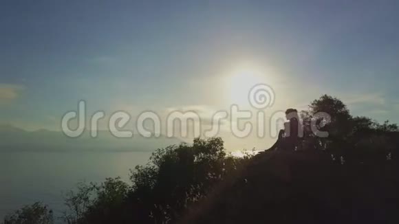 无人机从坐在岩石上的女孩在日出视频的预览图