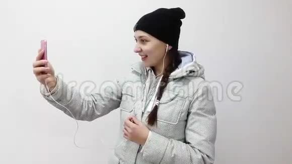 十几岁的女孩带着耳机在智能手机上用视频通话视频的预览图
