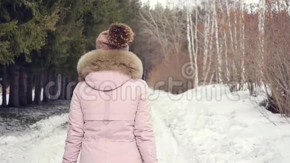 幸福美丽的女人在阳光明媚的日子里走在冬天的森林里慢动作视频的预览图