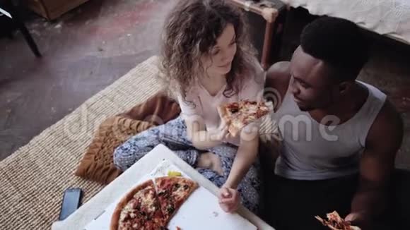 女人给男人提供比萨饼但自己吃多种族夫妇在吃快餐的时候玩得很开心视频的预览图