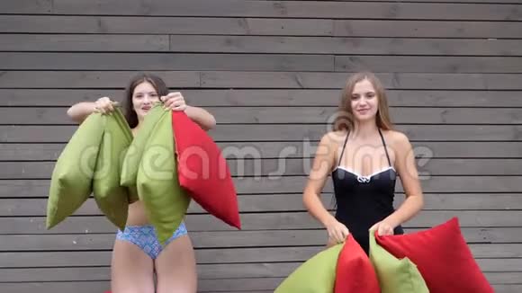爆笑朋友在背景木墙上玩女朋友穿着泳衣扔多色垫视频的预览图