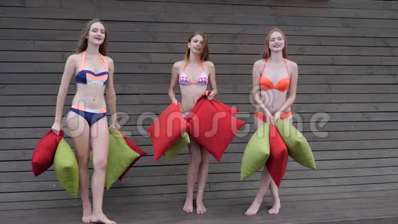穿着泳衣的女朋友向空中投掷多种颜色的垫子穿着泳衣的漂亮女孩参加聚会视频的预览图