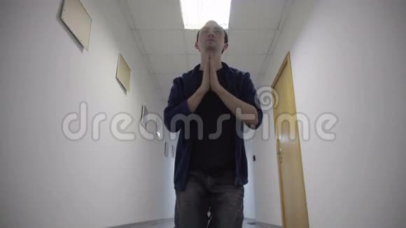 年轻人跪在白色走廊上祈祷视频的预览图