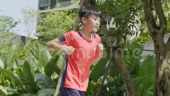 亚洲少年在花园里奔跑慢动作跳跃视频的预览图