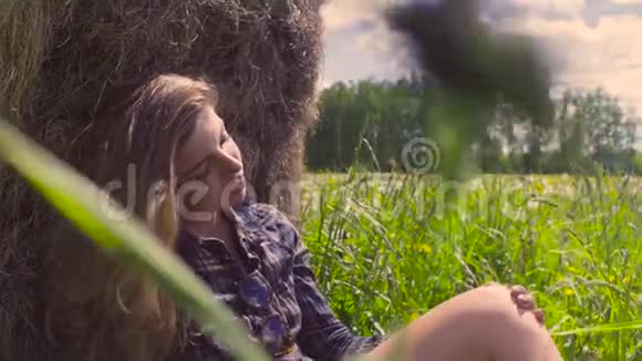 坐在草堆旁草地上的年轻女子视频的预览图