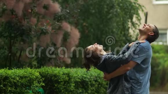 快乐的情侣一起在城市公园户外享受温暖的夏日雨视频的预览图
