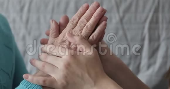 一个年轻的女人正在抚摸她祖母皱纹的手视频的预览图