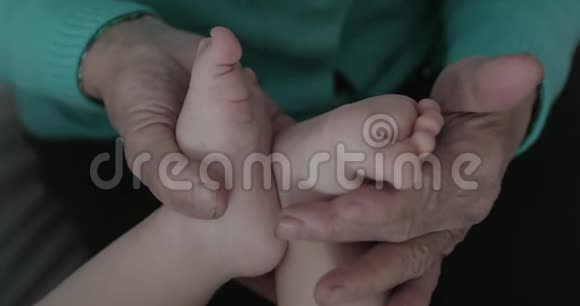 一个婴儿的特写她的脚在祖母的皱纹的手里视频的预览图