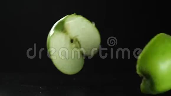 慢动作绿色苹果切片落在黑色背景高清慢动作视频的预览图