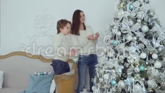 年轻的母亲和她的小儿子在圣诞树上挂着视频的预览图
