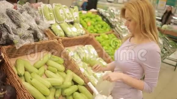 一个女人在超市的蔬菜货架上买蔬菜西葫芦视频的预览图