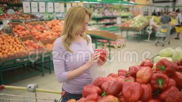 一个女人在一个蔬菜货架上的超市里买了贝尔胡椒视频的预览图